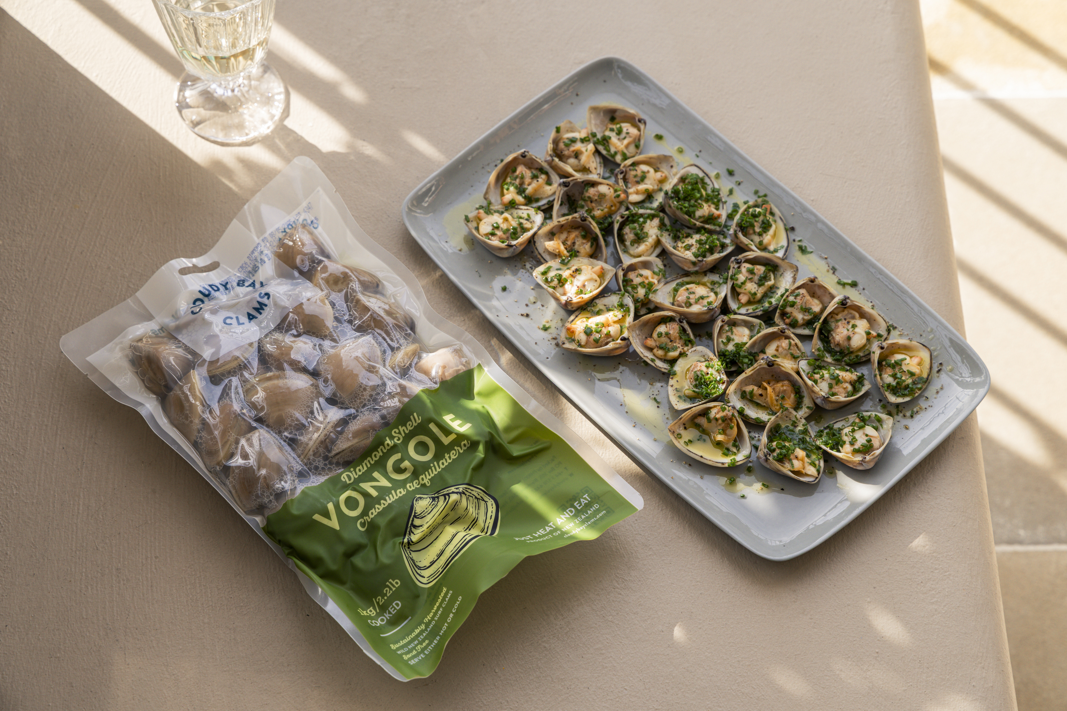Diamond Shell Vongole pack beside plated herbed clams