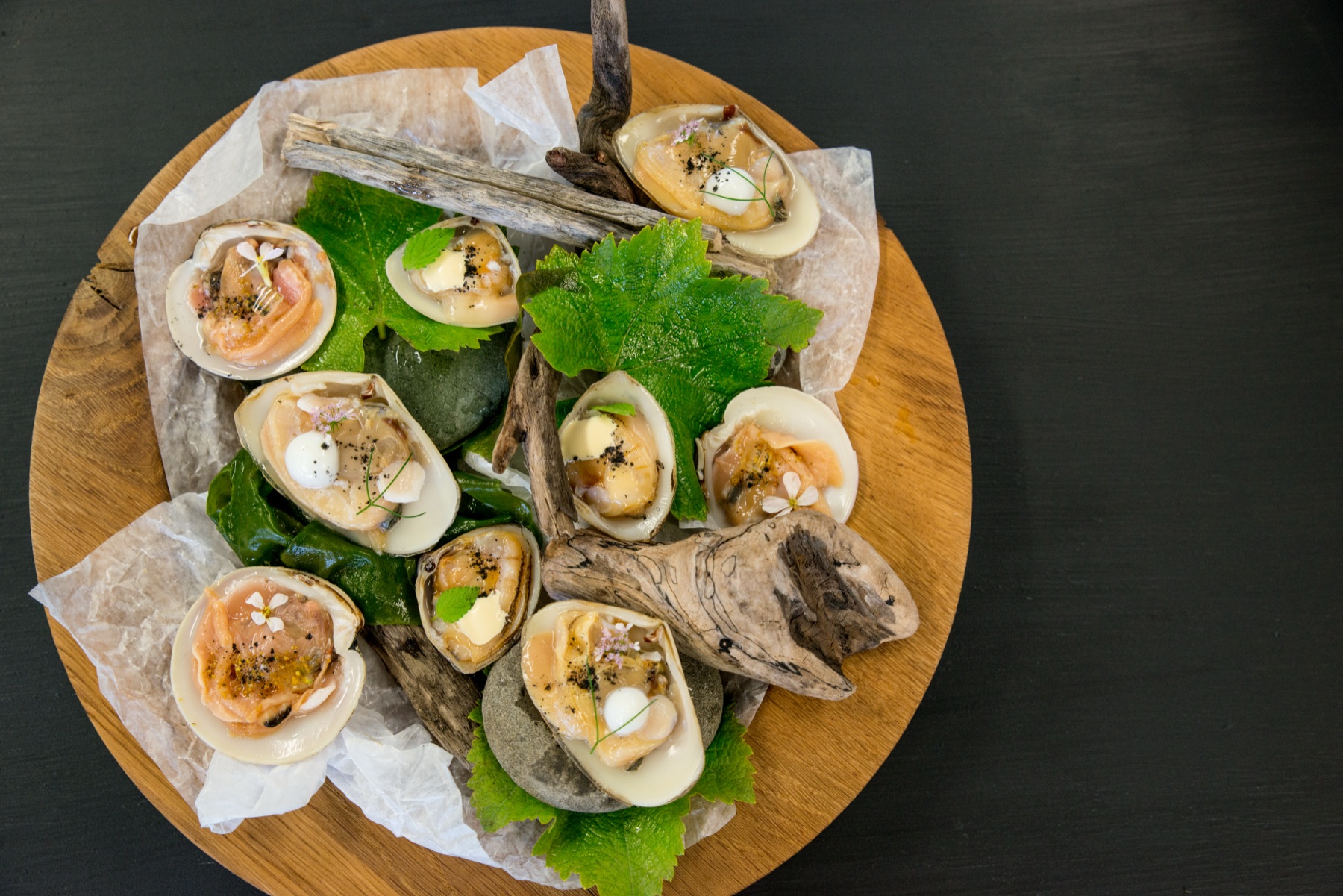 Raw clams on the half shell dressed with cream and dashi, served on a driftwood platter