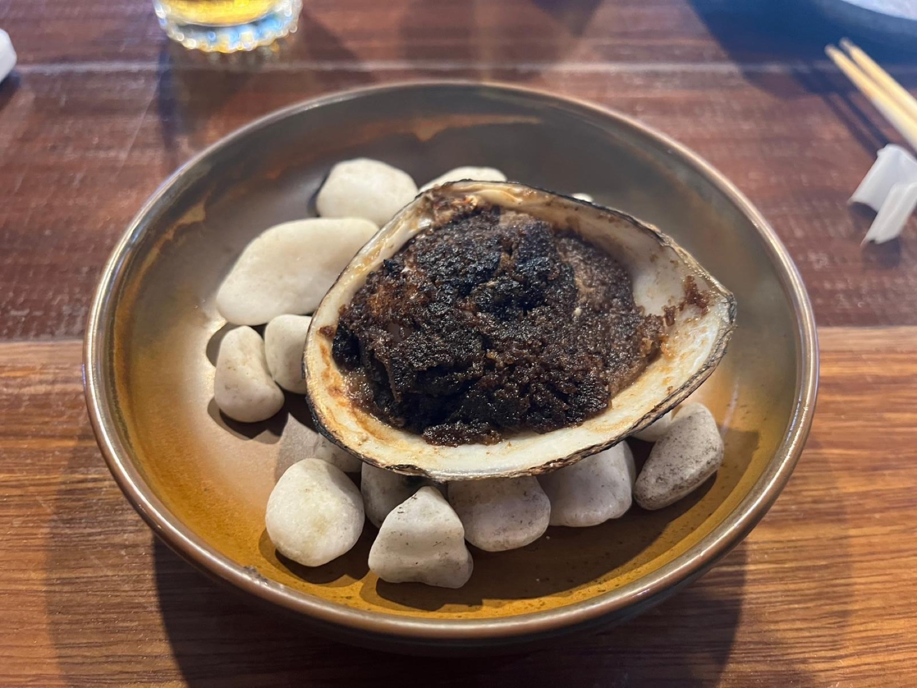 Storm Shell clam baked with a dark miso crust, served on river stones